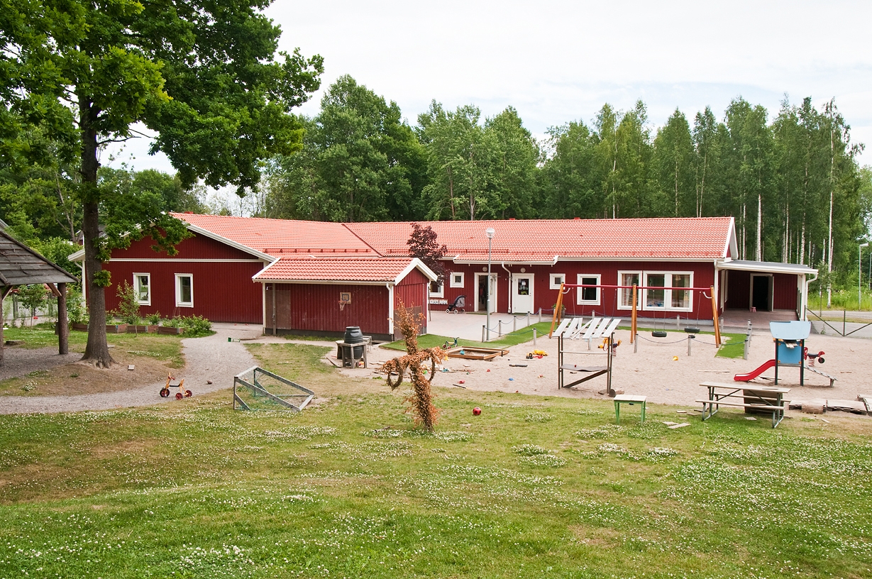 En röd förskola med en lekpark i förgrunden. 